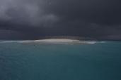 Ciel noir au dessus de l'îlot de sable blanc.